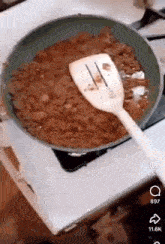 a frying pan filled with food and a spatula on a stove .