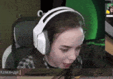 a woman wearing white headphones is playing a video game with a green background