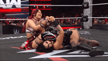 two women are wrestling in a wrestling ring with the letter w on the wall behind them