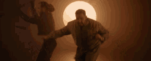 a man is standing in a dark room with a light behind him .