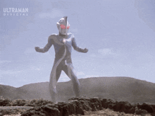 a man in a blue suit is standing in a field with the word ultraman on the bottom