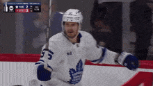a hockey player in a toronto maple leafs jersey holds a hockey stick