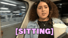 a woman with curly hair is sitting in a car with the word sitting above her