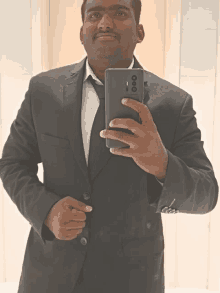 a man in a suit is taking a picture of himself with a cell phone