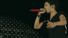 a man in a black shirt is singing into a microphone