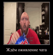 a bald man with a beard is eating a bag of potato chips in a kitchen .