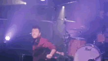 a man is playing drums on a stage in front of a microphone .