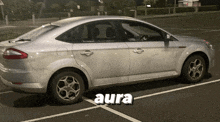 a silver car is parked in a parking lot and the word aura is on the bottom