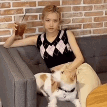 a woman is sitting on a couch with a dog and a drink .