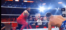 a man in a red dress is wrestling another man in a blue and white outfit in a wrestling ring .