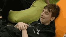 a young man wearing a black shirt that says freddy is laying on a bean bag