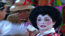 a woman dressed as a geisha is talking to a man wearing a hat .
