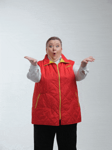 a woman wearing a red vest with a yellow zipper has her hands up