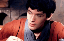 a close up of a man wearing a scarf and a red shirt
