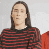 a woman wearing a striped sweater is making a funny face .