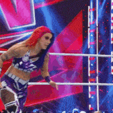 a female wrestler with red hair is standing in a ring .
