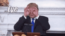 a man in a suit and tie is covering his eyes with his hands and the word eye is above him