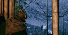 a person looking out a window at a mountain