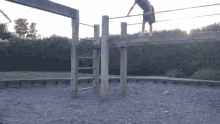 a person is doing a handstand on a wooden structure in a park