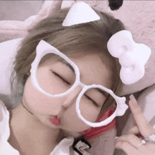 a girl wearing white glasses with a bow on her head