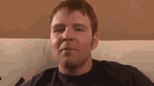 a man is sitting on a couch making a face .