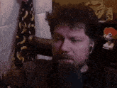 a man with a beard is talking into a microphone while sitting in a chair .