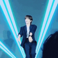 a man in a suit is dancing on a stage in front of a blue light beam .