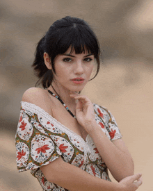 a woman wearing a floral off the shoulder dress and a necklace