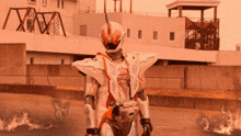 a man in a white and orange costume stands in front of a building with the letter x on it
