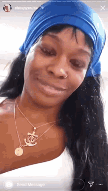 a woman wearing a blue headband and a gold necklace is smiling
