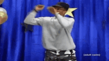 a man is standing in front of a blue curtain dancing .