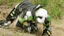 a person in a green and black costume is crawling in the grass