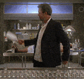 a man in a suit is standing in front of a shelf with bottles on it