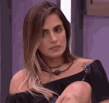 a woman wearing a black off the shoulder top and a necklace