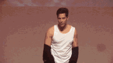 a man in a white tank top and black sleeves stands on a stage