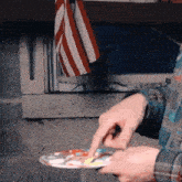 a person is holding a palette with a red white and blue flag behind them