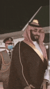 a man in a traditional costume is standing in front of an airplane .
