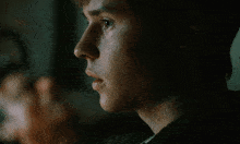 a close up of a young man 's face with a dark background