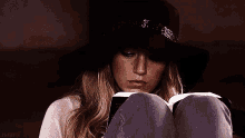a woman is sitting on a couch reading a book .