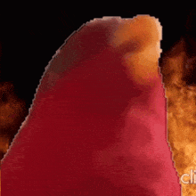 a red object is standing in front of a fire in a dark room .