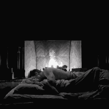 a man and woman laying in front of a fireplace