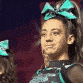 a man wearing glasses and a cheerleader outfit has a green bow in his hair