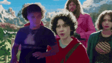 a group of people are walking in front of a mountain with a viggle.ai logo in the corner