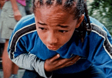 a boy in a blue shirt is holding his chest