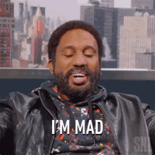 a man with a beard says i 'm mad in front of a city skyline