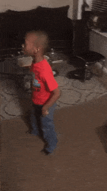 a young boy is dancing in a living room in front of a couch .