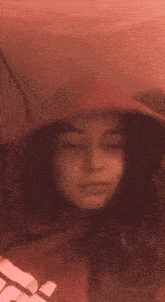 a girl wearing a red hoodie is laying on a bed