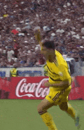 a soccer player celebrates a goal in front of a coca cola ad
