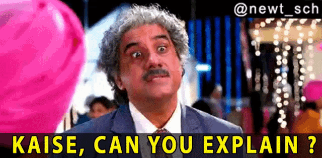 a man in a suit and tie is standing in front of pink balloons and says ' kaise can you explain ? '