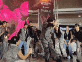a group of people are dancing in front of a robinsons galeria sign